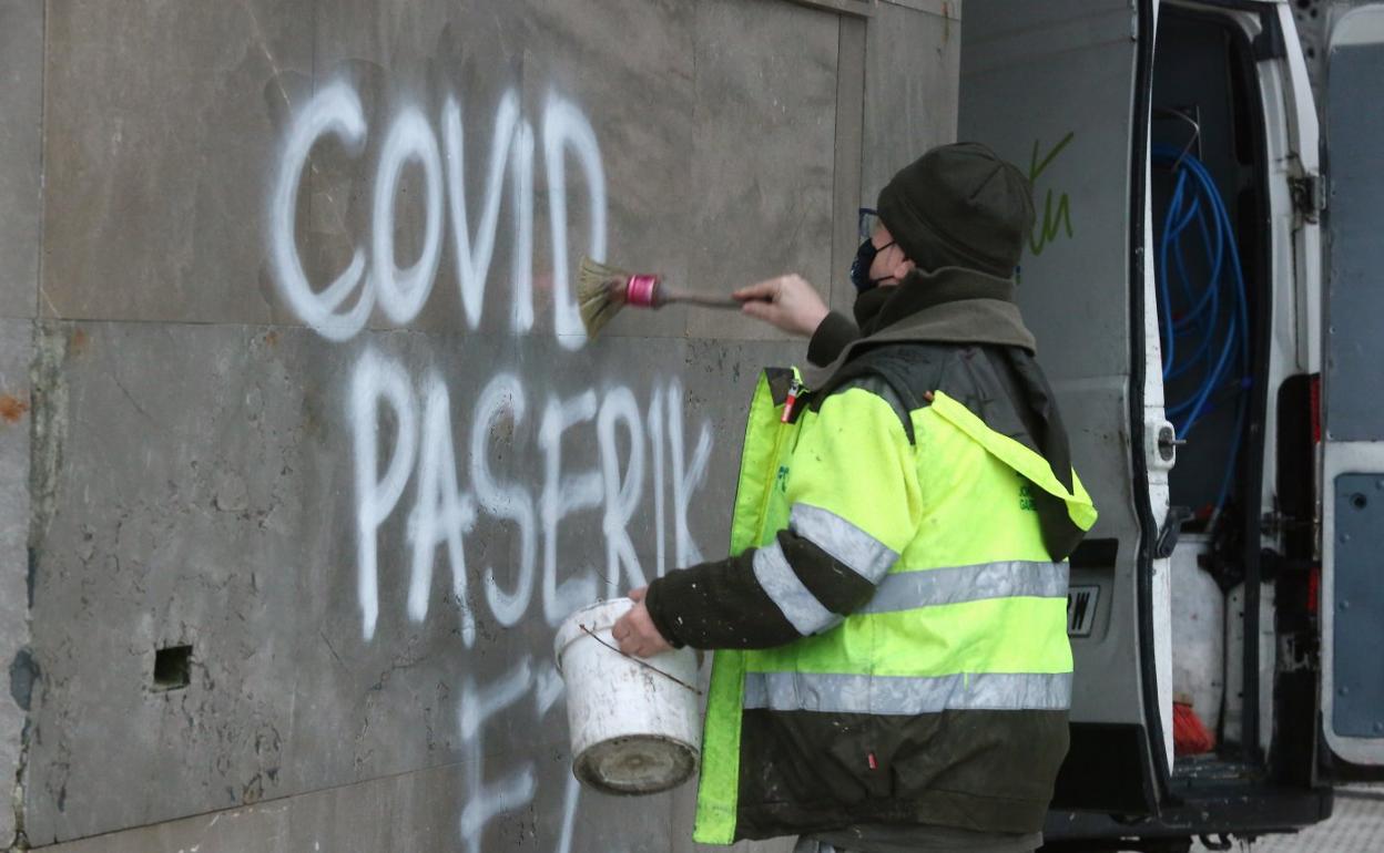 Un operario borra una pintada contra el pase covid en Donostia. 