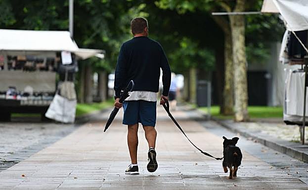 Un hombre pasea con su perro por las calles de Deba. 