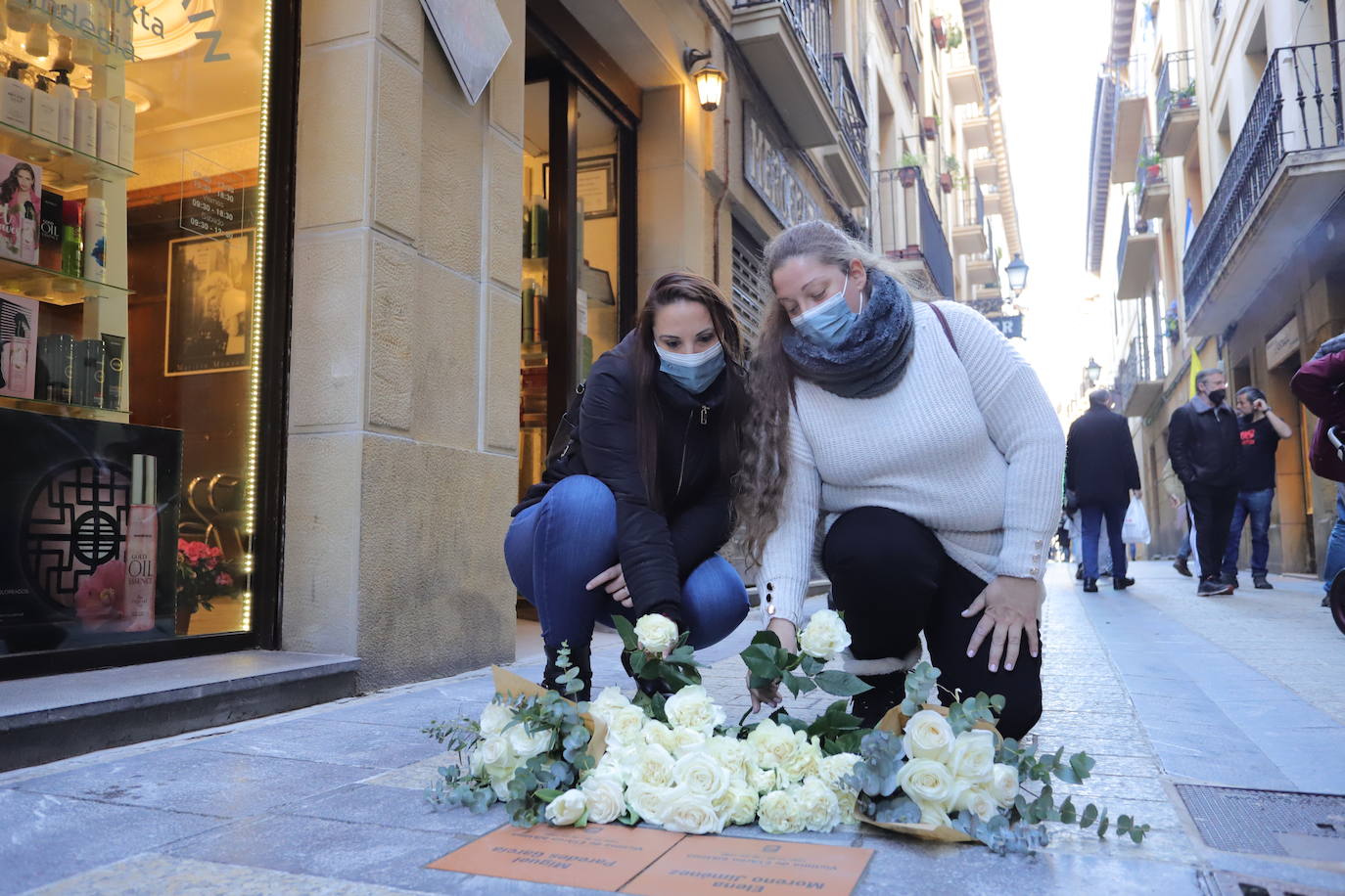 Tamara y Sherezade, las hijas de la pareja asesinada, colocan rosas blancas junto a las placas que recuerdan a sus padres.