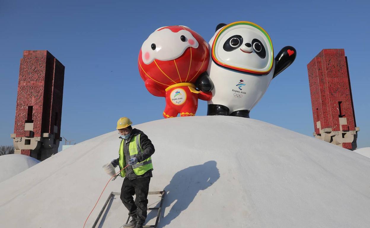 Un operario pinta junto a las mascotas de los Juegos Olímpicos de Invierno Pekín 2022. 