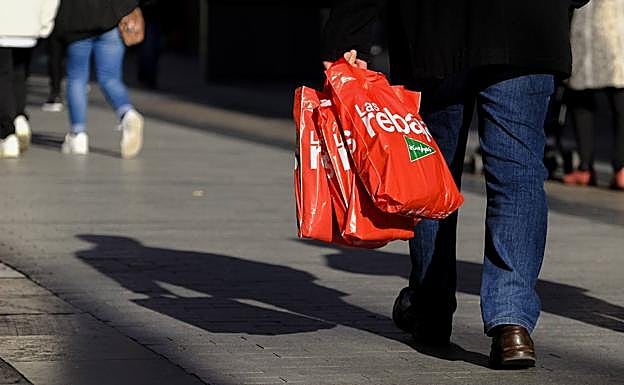 Un hombre camina con bolsas de las rebajas en una calle de Madrid. 