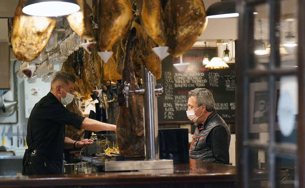 Cliente y trabajador con la mascarilla en el interior de un establecimiento