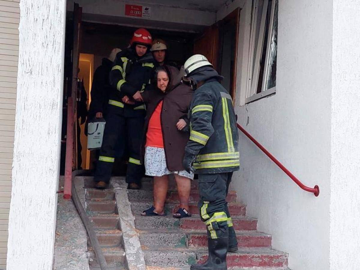 Una mujer es evacuada por miembros del equipo de rescate después de que los restos de un misil derribado dañaran un edificio residencial.