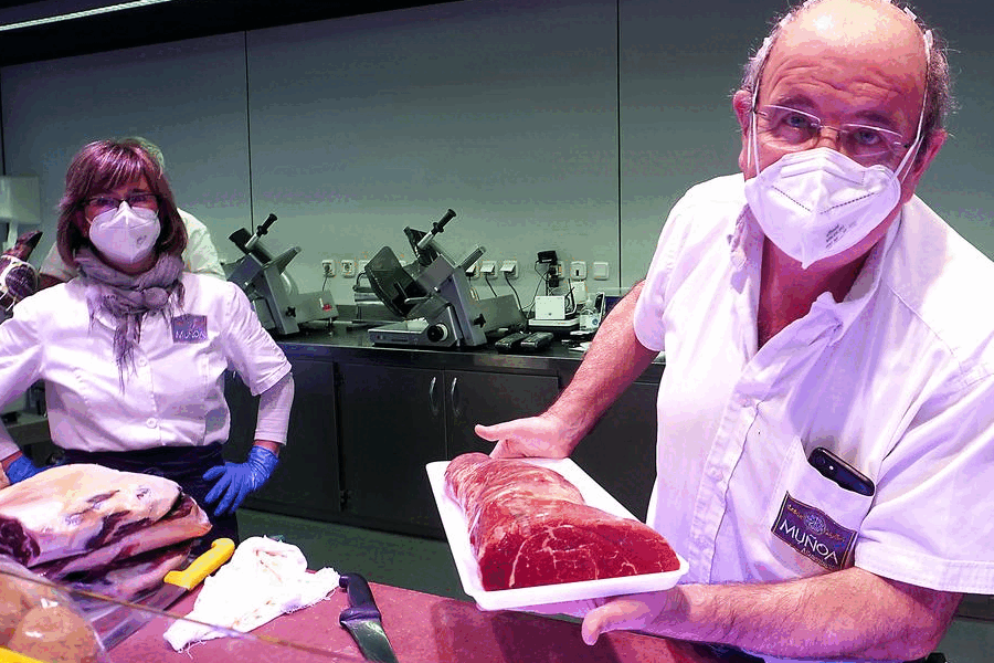 Maite y Javier muestran una pieza de carne ensu puesto del mercado San Martín..