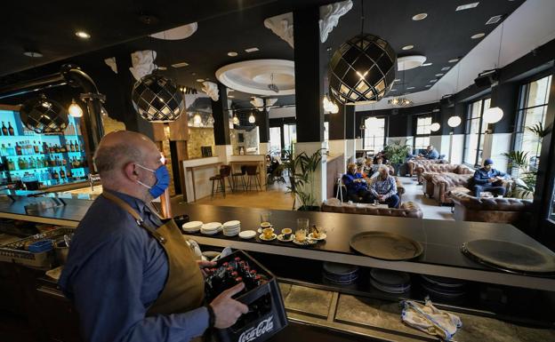 Imagen principal - Un empleado del bar Baluarte Donostia coloca unos refrescos. Nagore Abaigar prepara un café en el bar Xare de Tolosa. El bar de la Hípica de Loiola anuncia la subida temporal de precios en su carta de productos. 