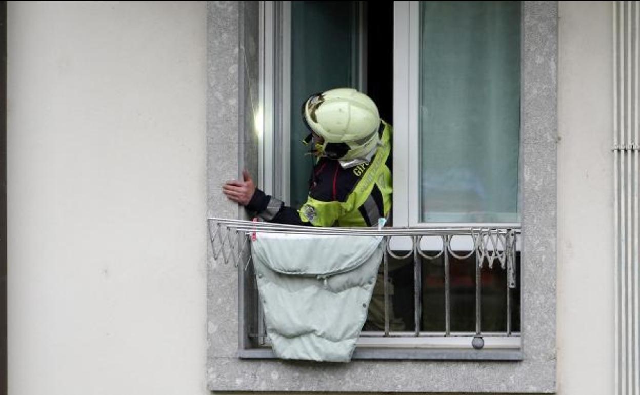 Un miembro del servicio de Bomberos de la Diputación Foral de Gipuzkoa en la ventana de la vivienda de Zaldibia donde ha ocurrido el trágico suceso