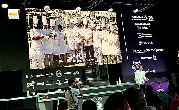 Eneko Atxa y, detrás, la mitica foto de la Nueva Cocina Vasca en el muelle donostiarra. 