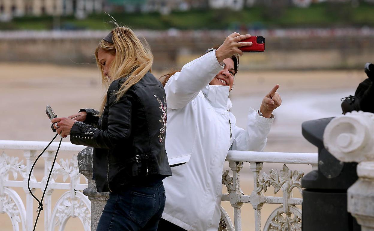Una mujer se saca una foto con su teléfono en el Paseo de La Concha.