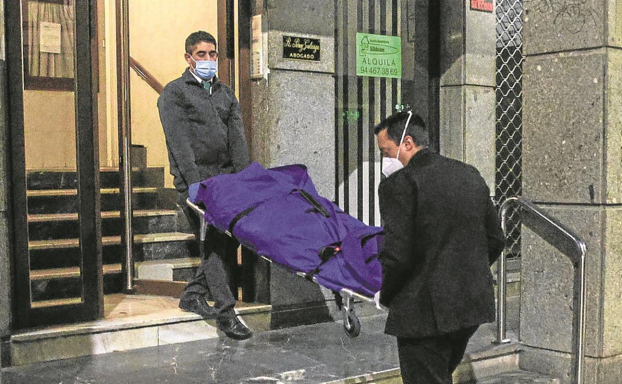 Empleados de una funeraria extraen el cadáver del domicilio donde se produjo el crimen de Erandio.