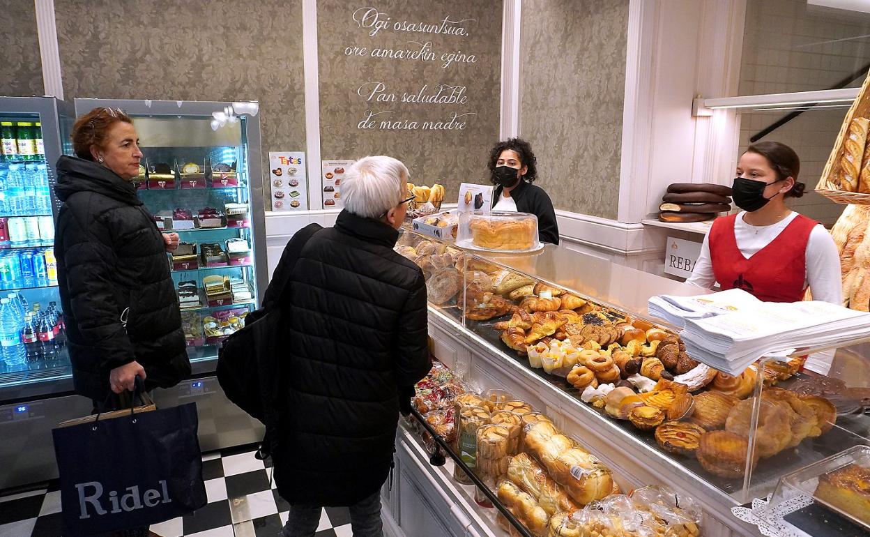 Dos trabajadoras de una panadería de Donostia atienden con mascarilla a dos clientas. 