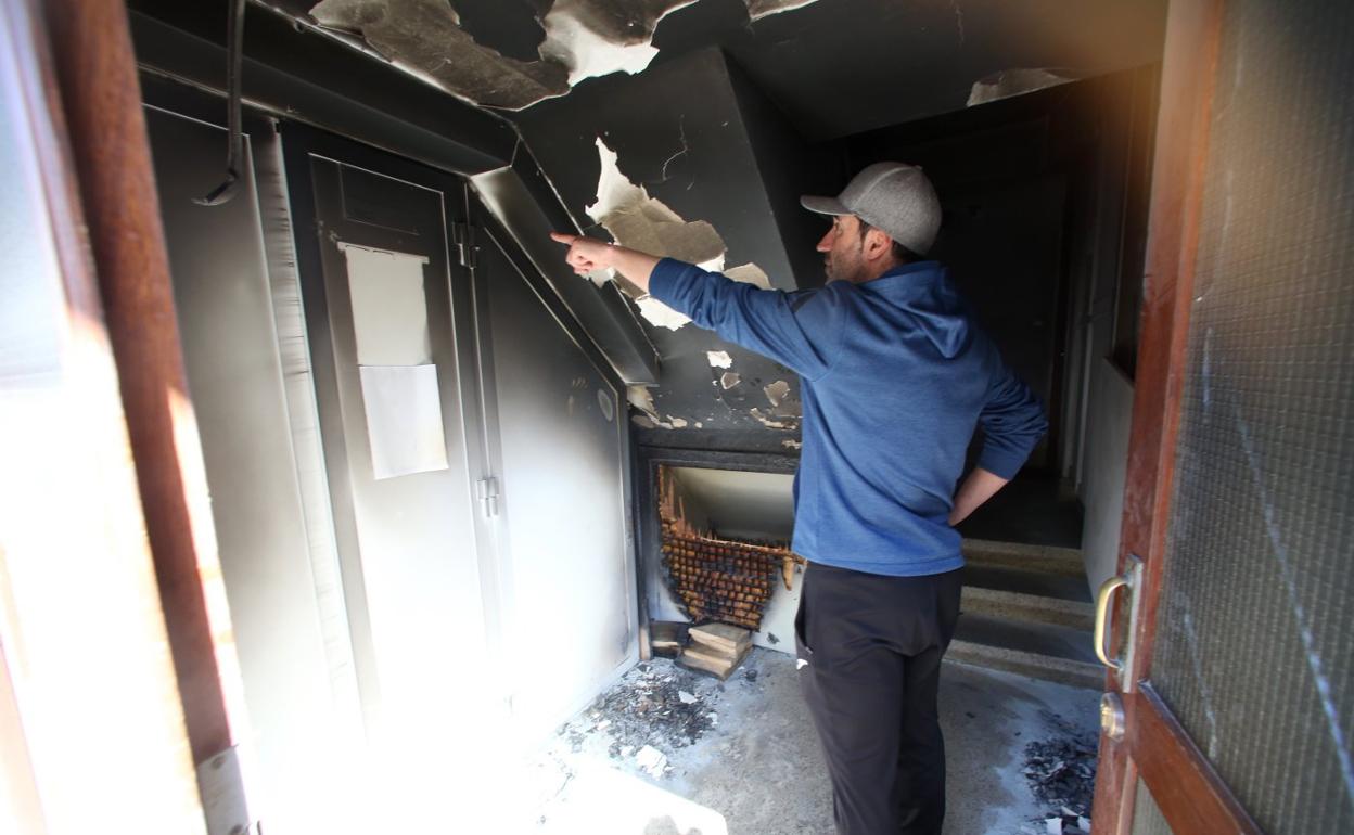 Un vecino señala los desperfectos en el techo, justo donde ardió el coche de niño que provocó la humareda en el portal. 