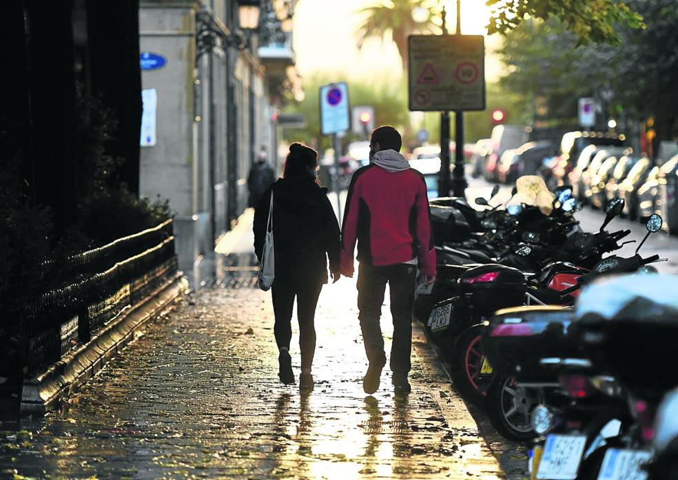 Una pareja pasea de la mano por una calle de San Sebastián. 