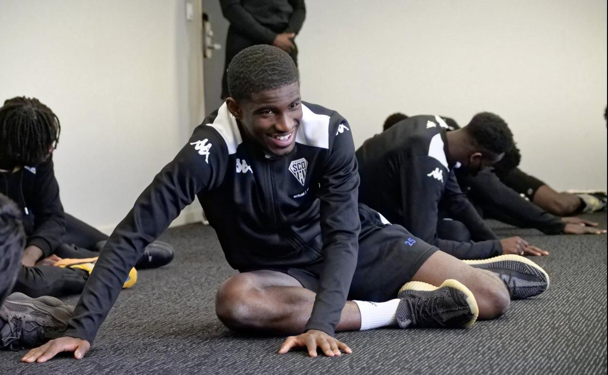 Mohamed-Ali Cho realiza estiramientos en una habitación junto al resto de sus compañeros del Angers. 