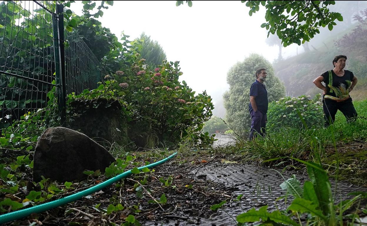 Juan y Cristina llegan a ver los efectos del incendio desde su caserío Aralegi Goikoa. A la izquierda, junto a la manguera, una pieda calcinada que cayó del monte y saltó una valla. 