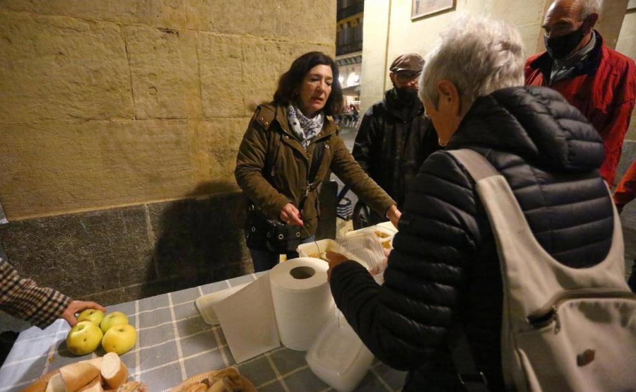 Voluntarios preparan la cena a personas sin techo en los arkupes de la plaza de la Constitución. 