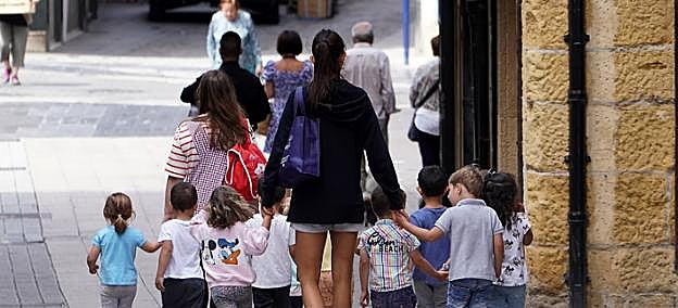 Varios niños caminan por una calle de Lezo junto a sus monitoras. 