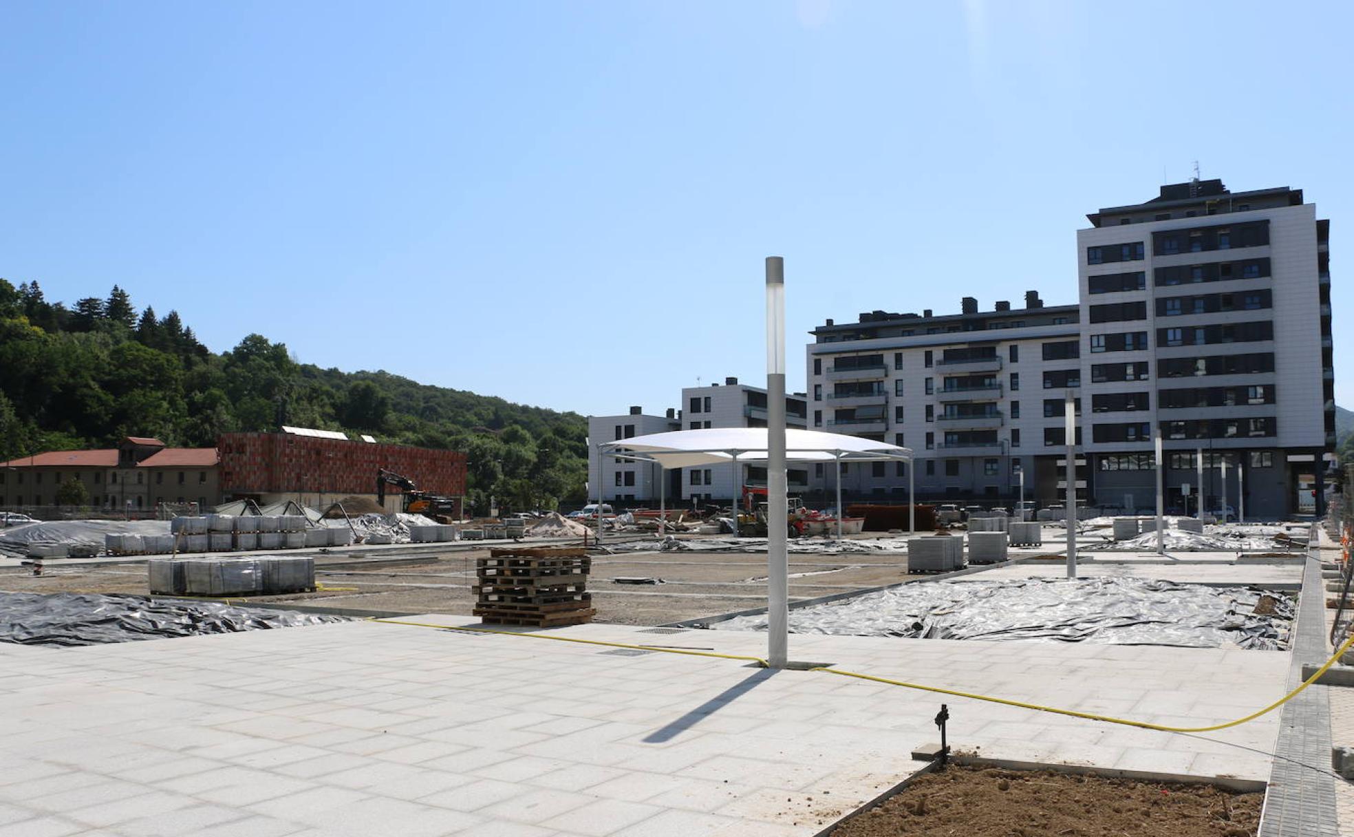 La plaza Arteleku de Txomin, con parte del pavimento colocada, farolas y la cubierta sobre la zona de juegos infantiles. Al fondo, el convento de Kristobaldegi.