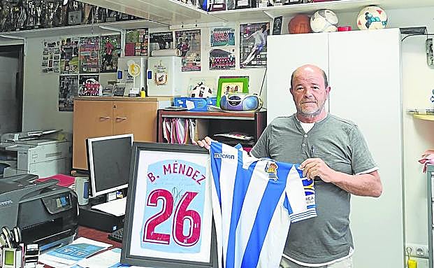 El presidente del Santa Mariña, Xosé Carlos Blanco, sostiene un cuadro con una camiseta regalada por Brais Méndez y la elástica de la Real, en su despacho.