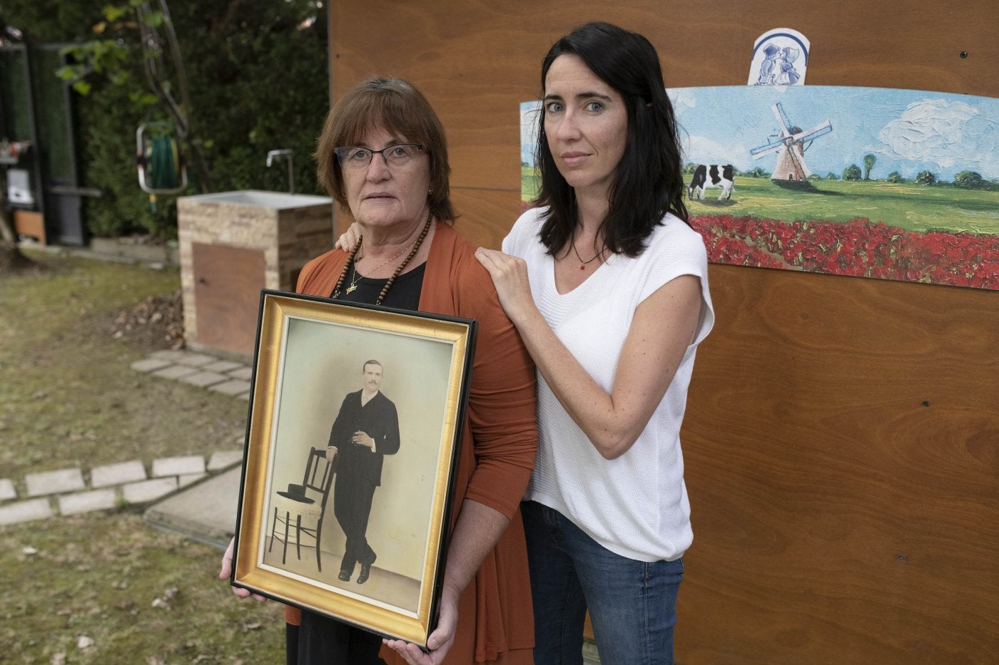 Naiara y su ama AnaMaría sujetan elretrato de su bisabuelo. 