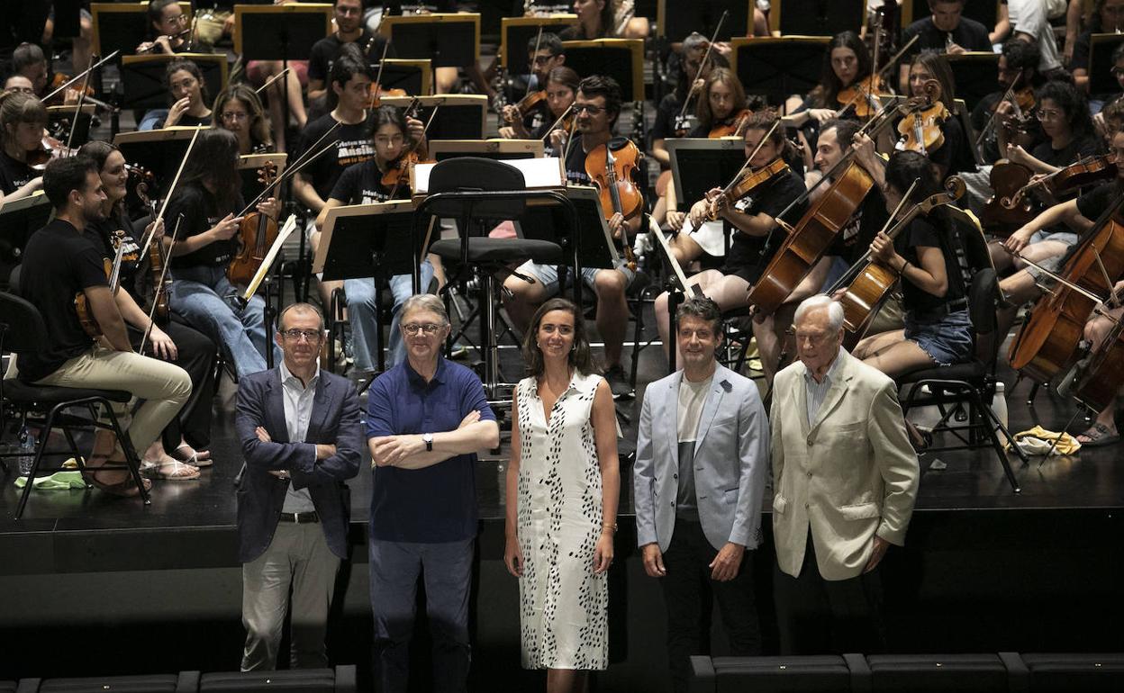 Organizadores del evento con los miembros de la orquesta detrás. 