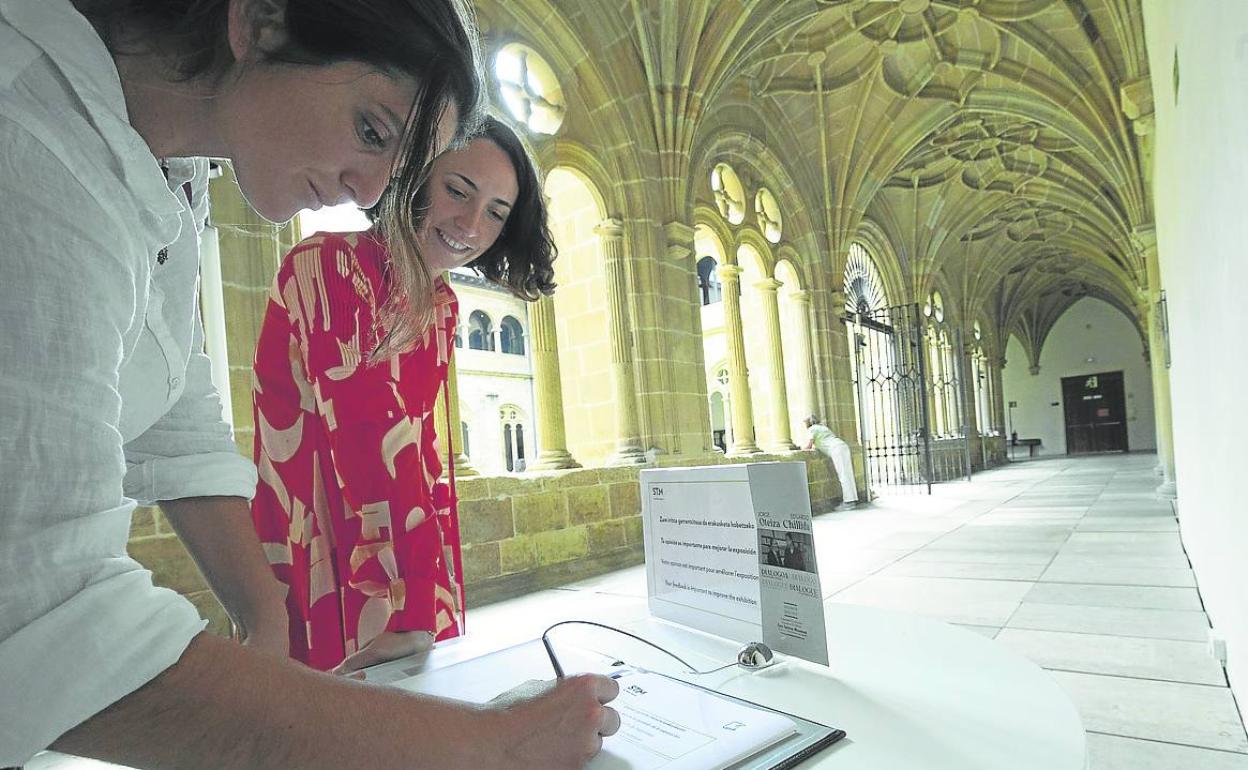 Visitantes anotan sus impresiones en el cuaderno instalado a la salida de la muestra. 
