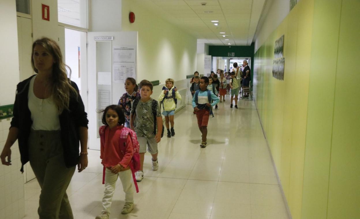 Varios niños se dirigen a clase siguiendo a la profesora. 