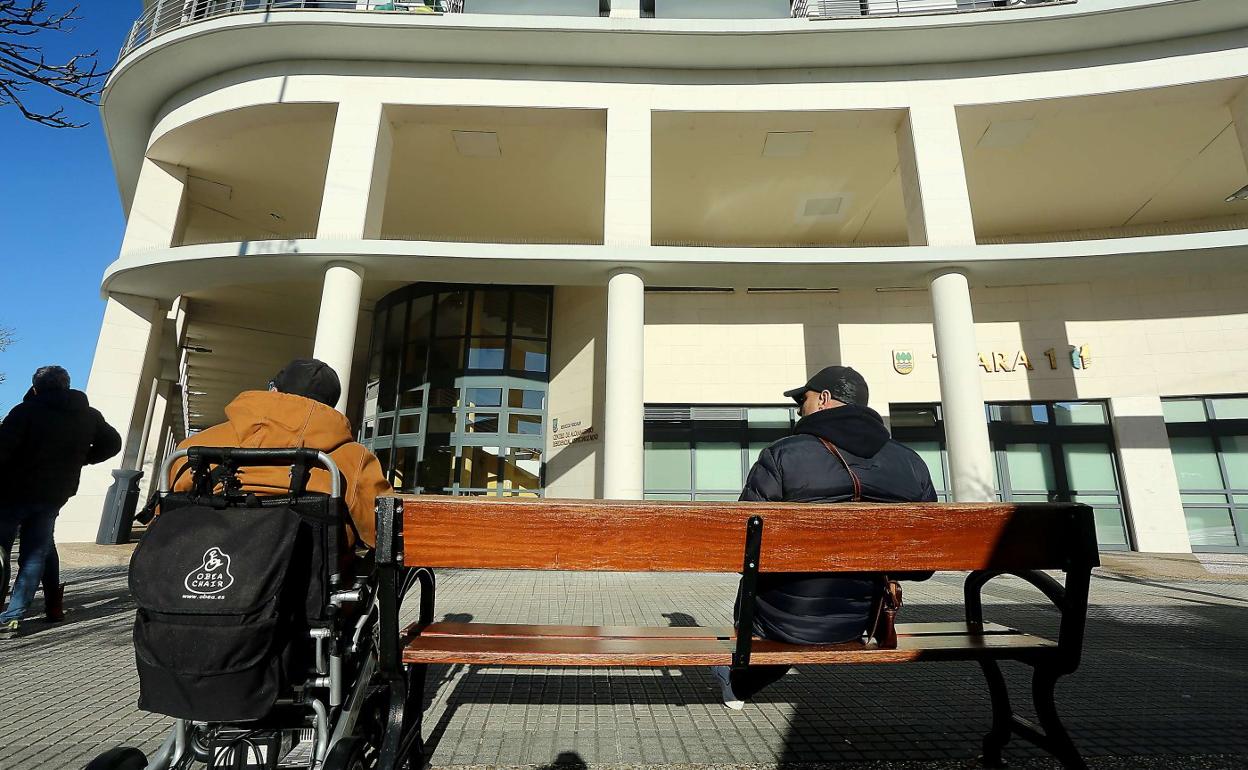Dos hombres toman el sol junto a la entrada del centro de mayores Txara 1 de San Sebastián. 