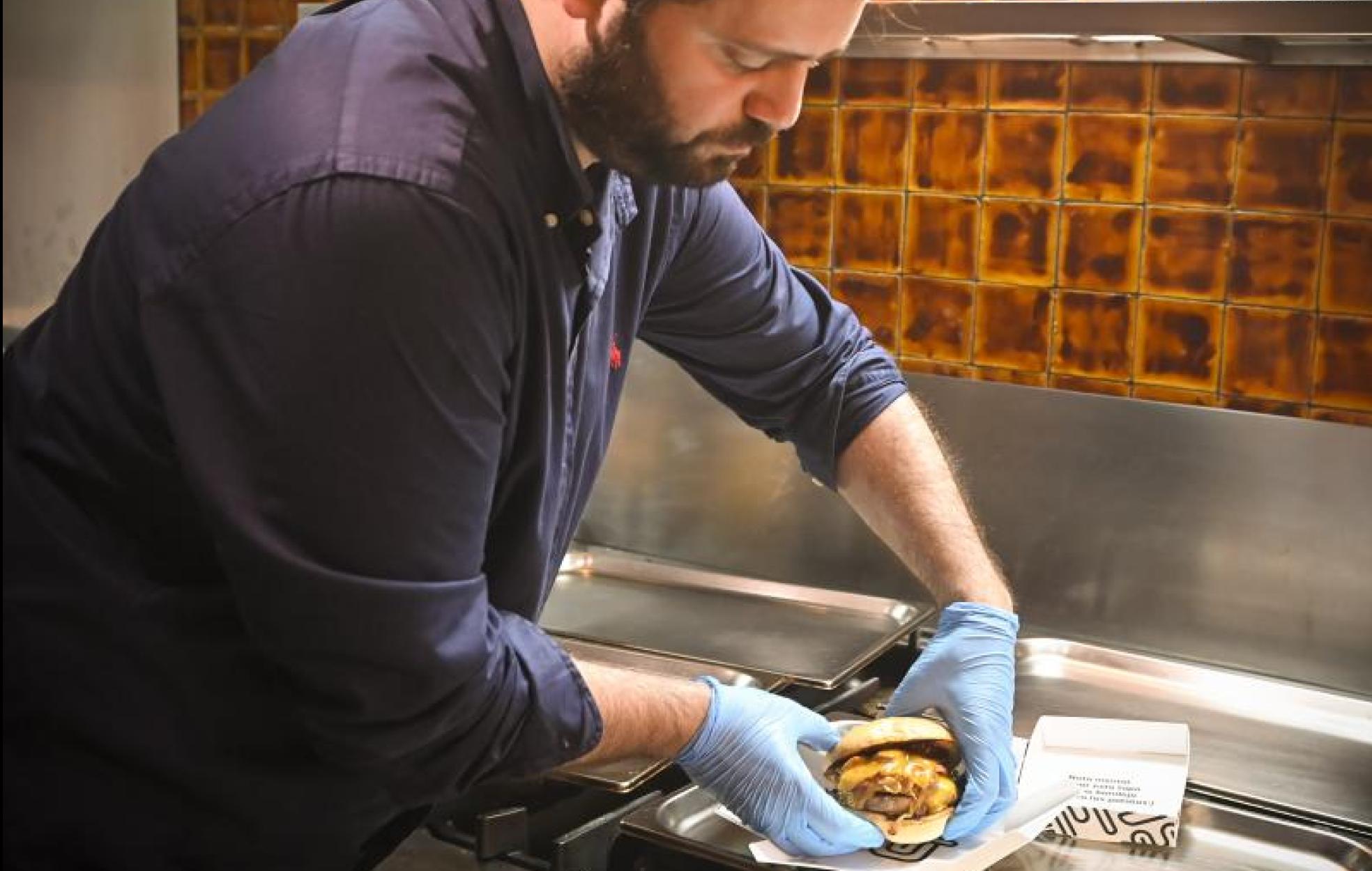 Luis Tovar empaqueta una de las hamburguesas que preparan desde las cocinas de Gow Delivery. 