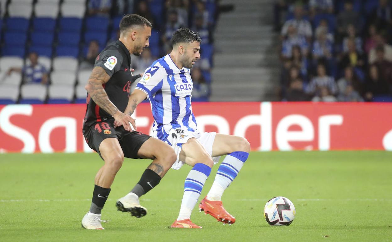 Rico protege el balón ante Sánchez. 