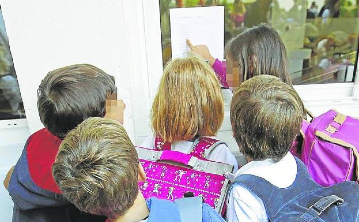 Varios niños ojean una nota informativa a la entrada de un colegio. / 