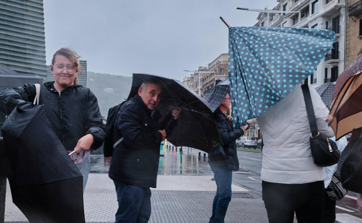 Ciudadanos se protegen del viento y la lluvia en San Sebastián.