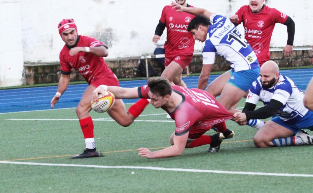 Lander Mujika se dispone a posar el oval tras la línea de marca pese al agarrón de un rival. 