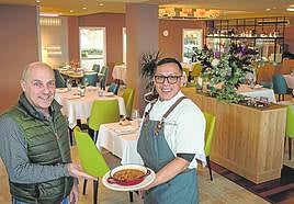 Ángel Ibarlucea, junto a un camarero, muestra una de las múltiples creaciones del Ikuspegi en su acogedor comedor.