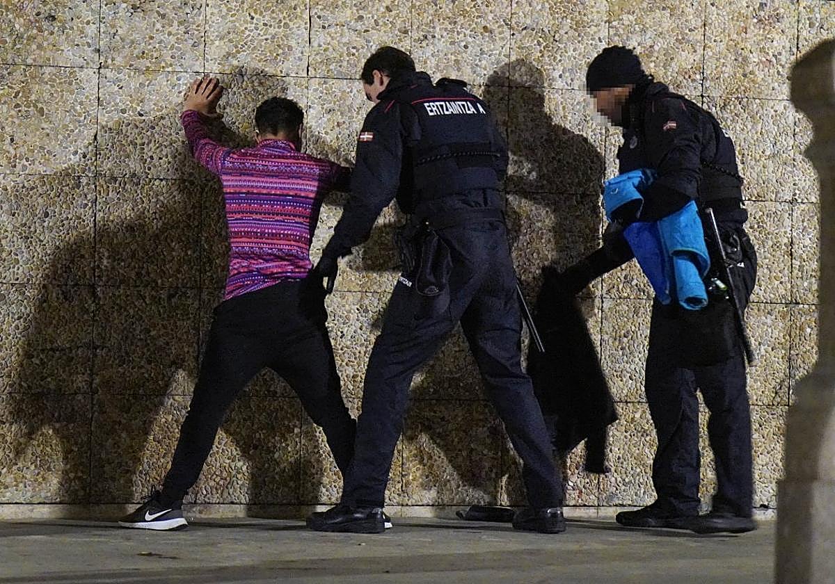 Dos agentes de la Ertaintza realizan un cacheo a un varón en los bajos de La Concha, en Donostia.
