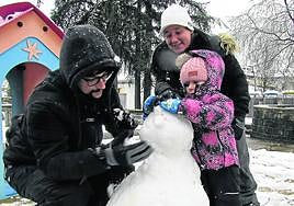 La pequeña Nora, de 4 años, haciendo un muñeco de nieve en Arrasate con ayuda de sus padres.