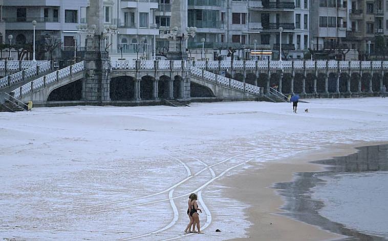 Imagen principal - Una fina capa de nieve cubrió a primeras horas la playa de La Concha. La nieve comenzó a caer con fuerza en Donostia a primeras horas de la tarde. La nieve tiñe de blanco la estación meteorológica de Aemet en Igeldo.