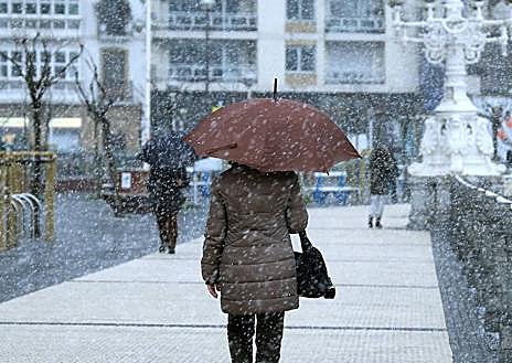 Imagen secundaria 1 - Una fina capa de nieve cubrió a primeras horas la playa de La Concha. La nieve comenzó a caer con fuerza en Donostia a primeras horas de la tarde. La nieve tiñe de blanco la estación meteorológica de Aemet en Igeldo.