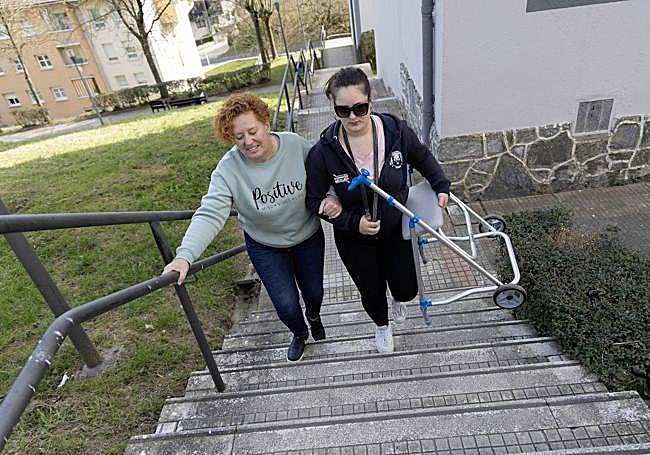Maite Fernéndez recibe ayuda para subir unas escaleras.