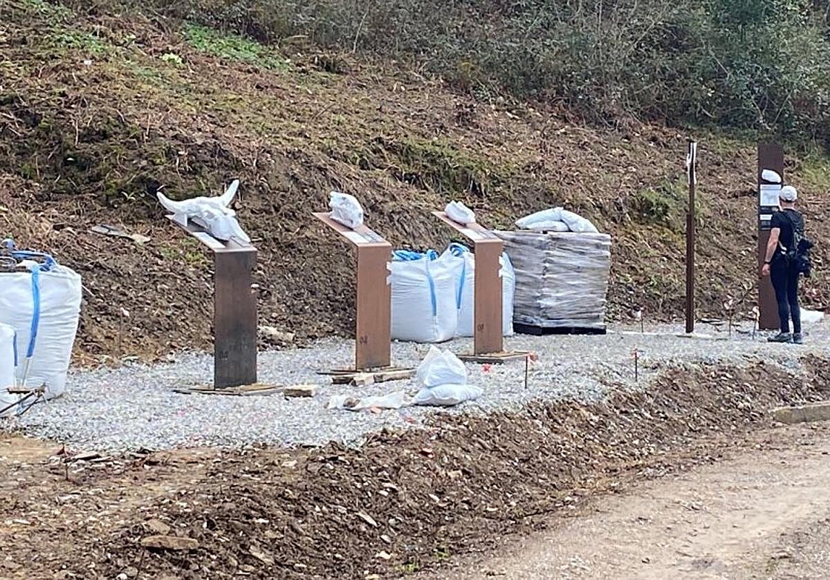 Tótems en el camino. Una caminante observa algunos de los elementos de la ruta.