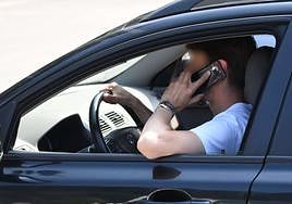 Un conductor habla por el móvil mientras conduce su vehículo.