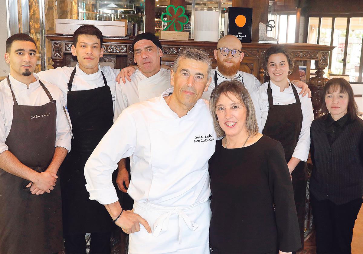 Eva Hernández y Juan Carlos Caro posan junto a su equipo en la entrada del restaurante Zelai Txiki. En las imágenes más pequeñas, se pueden ver la entrada, los dos comedores interiores y la cava de vinos.