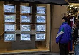 Dos jóvenes observan el escaparate de una imobiliaria donostiarra.