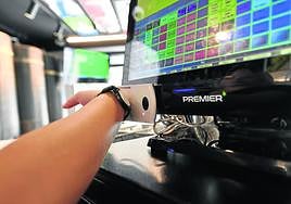 Un trabajador del bar Campus de San Sebastián ficha con su pulsera telemática en el ordenador del establecimiento.