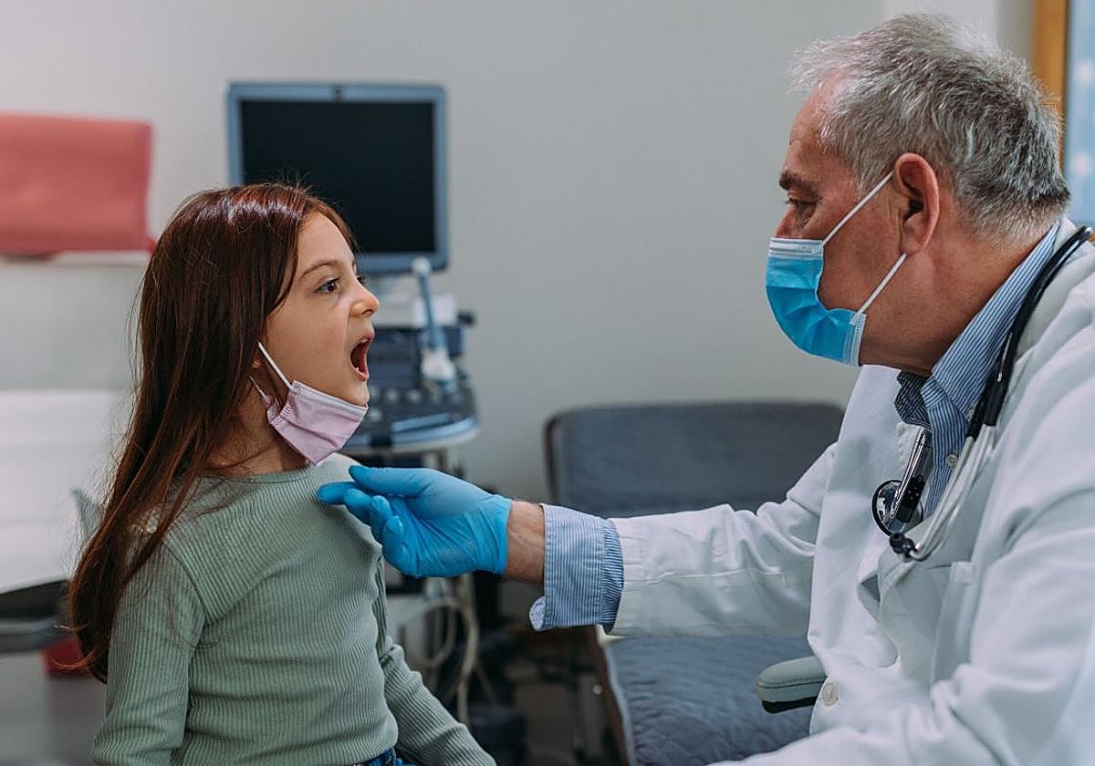 Un pediatra atiende a una niña en su consulta.