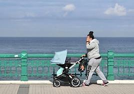 Mujer pasea a un bebé en un día soleado.