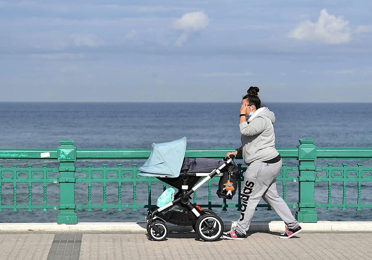 Mujer pasea a un bebé en un día soleado.