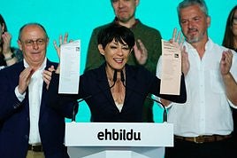 Iriarte enseña las papeletas de EH Bildu mientras Izagirre aplaude a su izquierda.