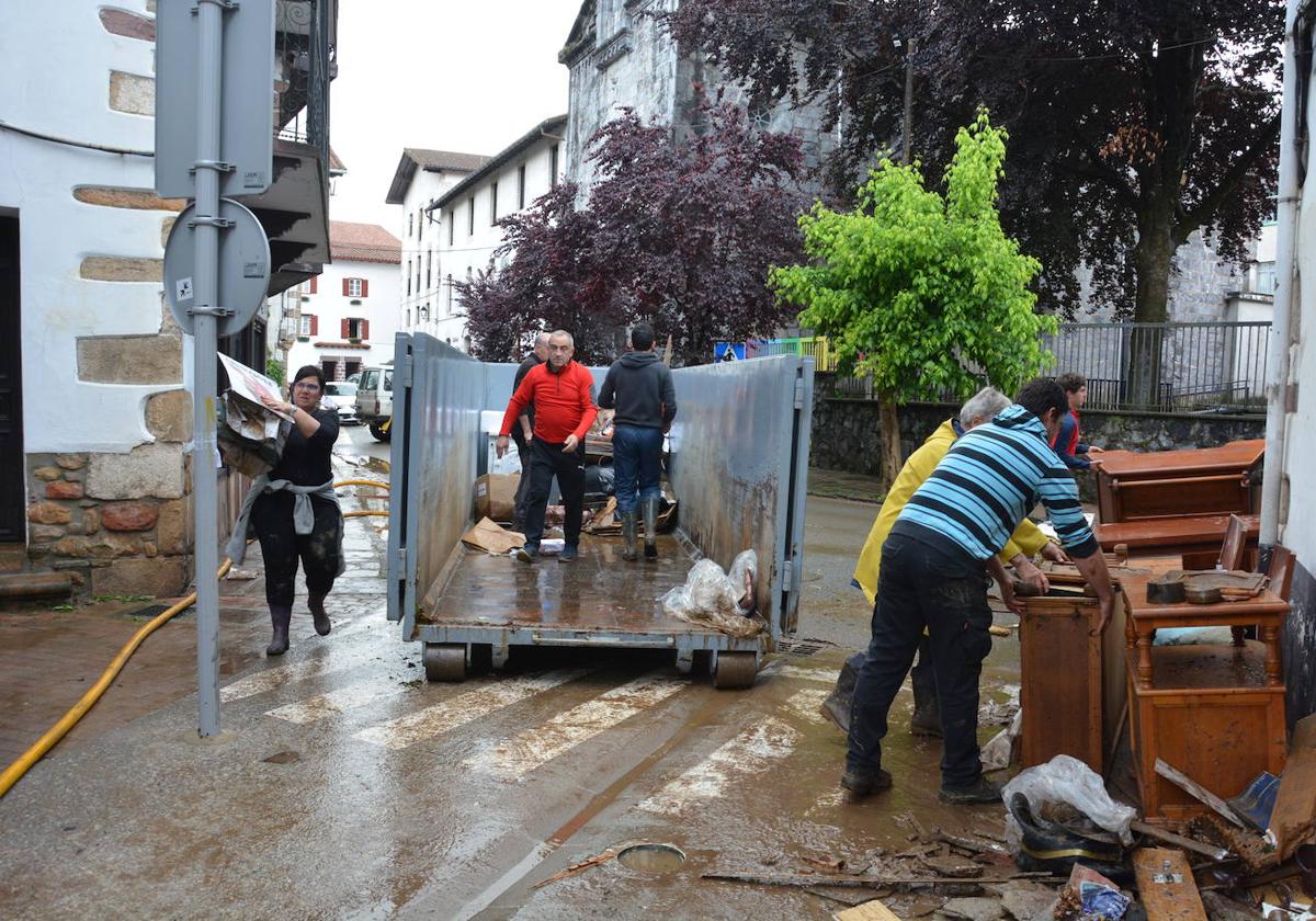 Vecinos de Bera a primera hora de la mañana limpiando calles y locales.