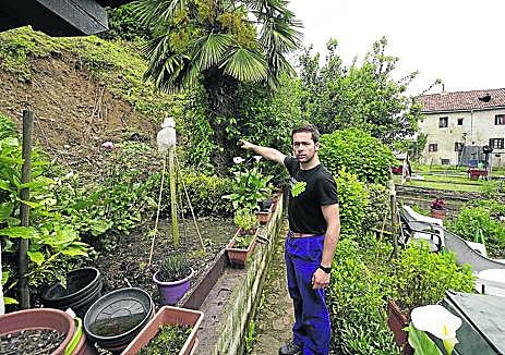 Imagen secundaria 1 - Eluska, hija de Coro, se asoma a su coche junto al pequeño Janur. El agua entró hasta los asientos y ahora, además del barro, el motor no arranca; Xuban señala el lugar donde el monte se desprendió, justo detrás de la casa donde vive su pareja, Leyre, con su familia en Lesaka y Edurne y Karlos terminan de limpiar la consulta de fisioterapia de este último, que hoy tiene que abrir porque tiene citas desde las 9.00 horas. 