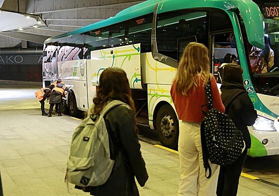 Usuarios hacen cola para subirse al autobús, mientras los inspectores de la Diputación inspeccionan el vehículo.